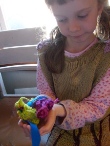 K holding her crocheted bird by the kitchen window