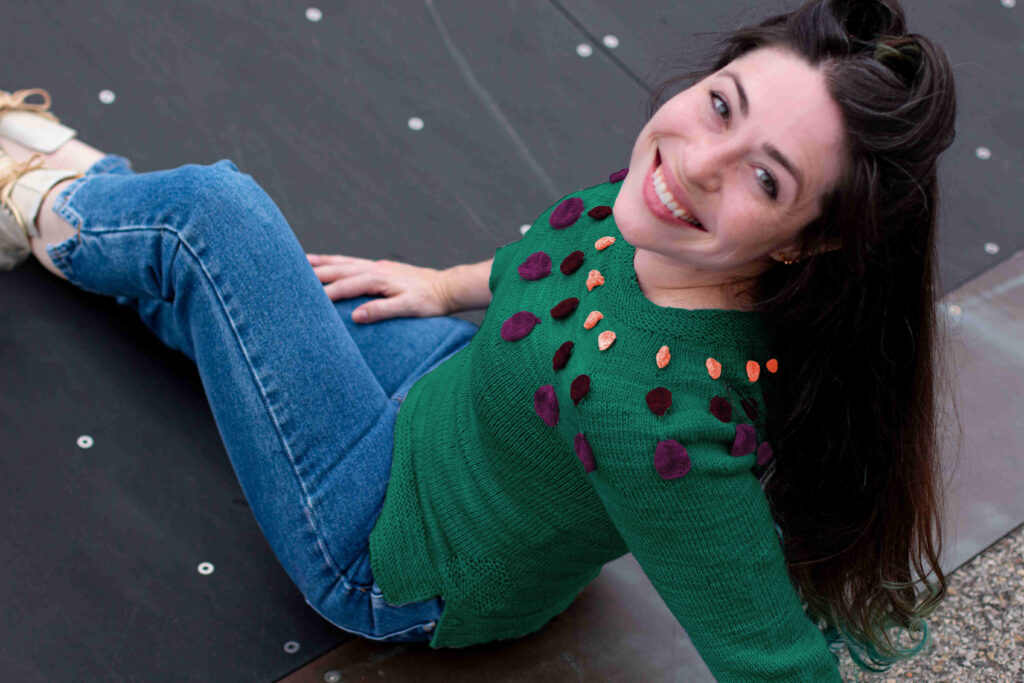 Woman smiling at camera wearing a fitted Circle Dance Sweater digitally altered to appear knit in a green colorway from Space Cadet Yarns