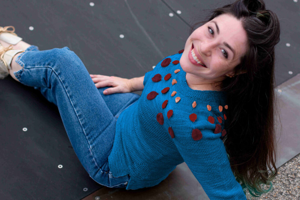 smiling woman looks over her shoulder in digitally altered blue Circle Dance Sweater knit from Space Cadet yarns