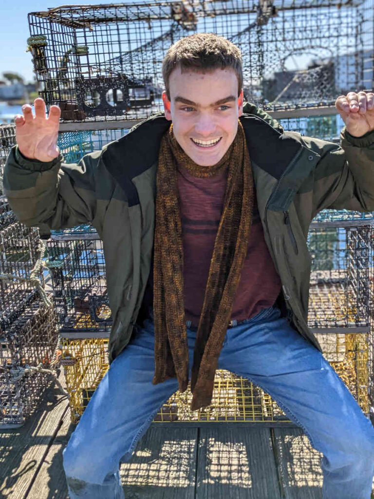 Newport Scarf on Matthew pretending to be a crab, in front of Lobster pots.