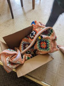 Peach and white granny Square Afghan in a delivery box