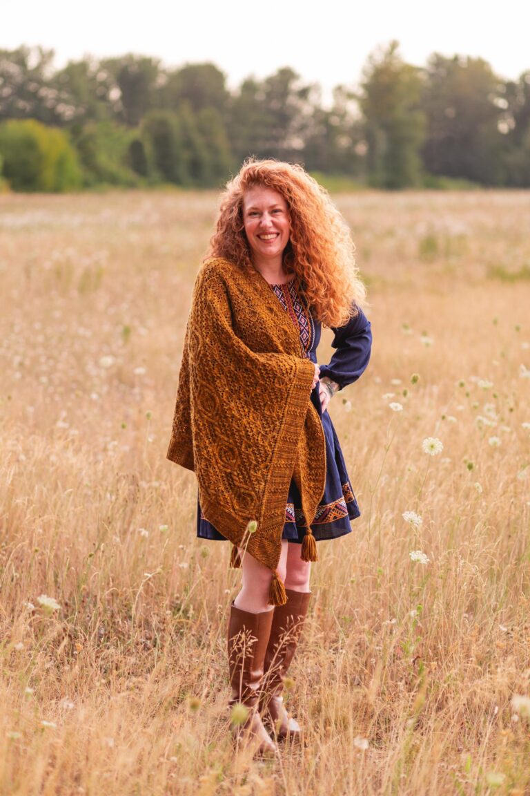 Smiling woman wears the Hollywood and Vine shawl in a meadow. Photo by Elizabeth Zimmerman of Western Rose Studios.