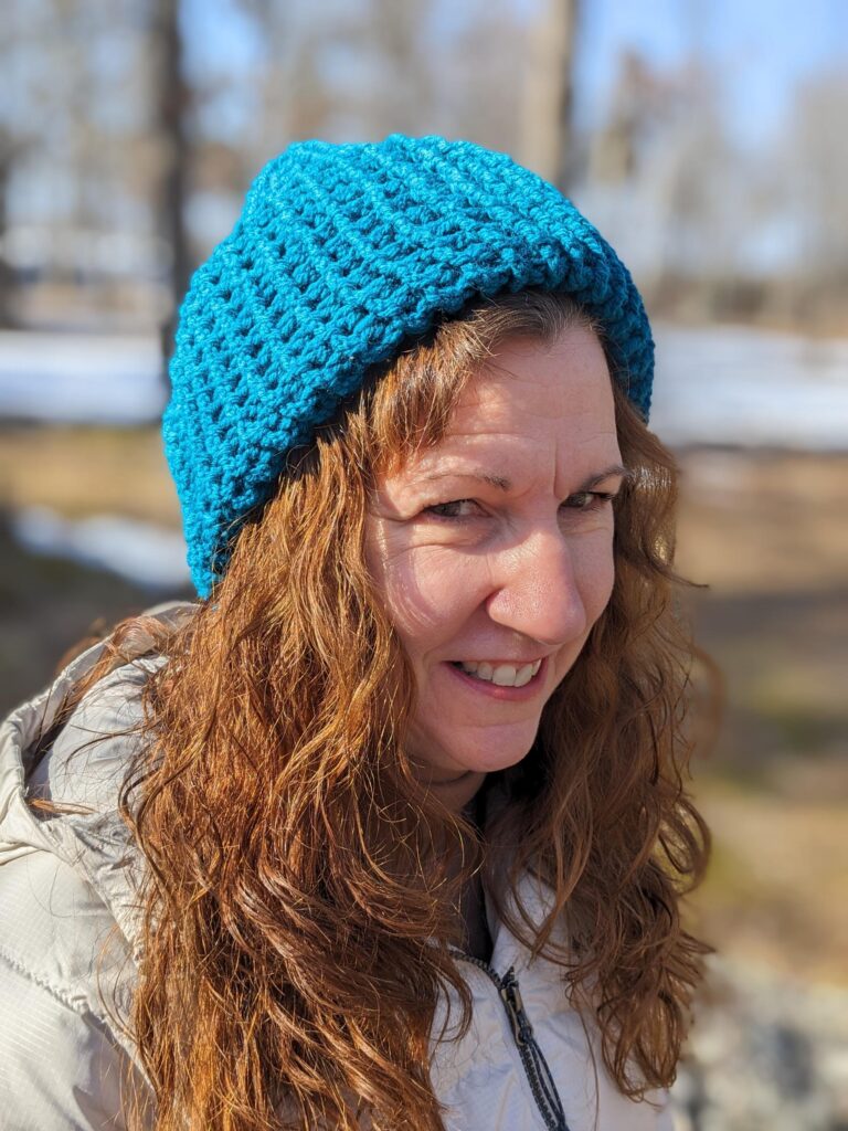 Woman smiles up at the camera wearing a Mether hat