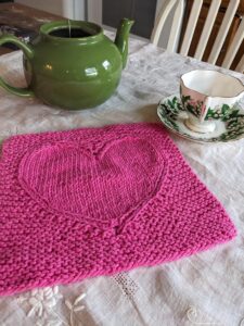 Merry Heart cloth shown on a white embroidered cloth with green tea pot and tea cup